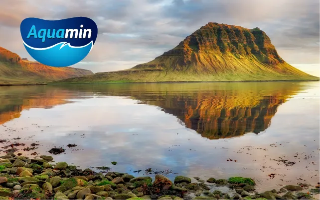 Panoramatický výhľad na jazero s horou a nálepkou Aquamin